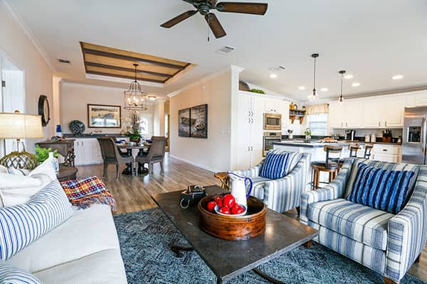 Rexmere Luxury Series Living room with large open area, ceiling fan a custom wooden tray ceiling.