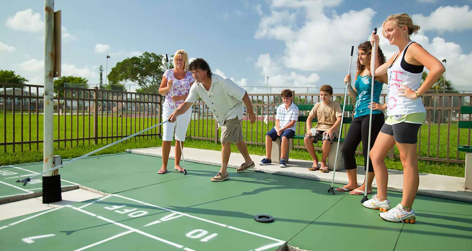 A family of five enjoying a game of shuffleboard at the Rexmere Village athletic facilties.
