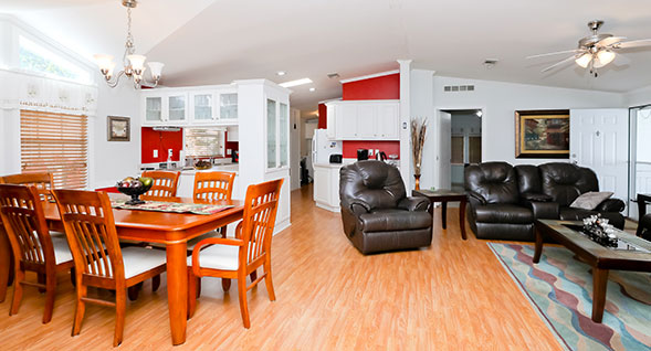 Open concept living room and dining room features hardwood laminate flooring and ceiling fan