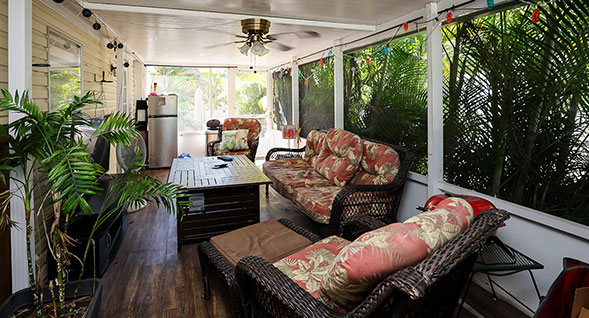 Spacious screened-in porch at Trailbend Terrace Rexmere Village featuring ceiling fan, wood-look flooring, comfortable outdoor seating surrounded by g