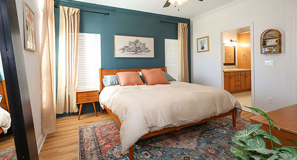 Spacious primary bedroom featuring wood-look flooring, designer accent wall, abundant natural light, and direct access to the ensuite bath.