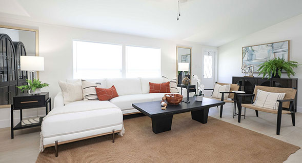 Bright and spacious open-concept living room with designer furnishings, architectural beam accents, abundant natural light, and modern coastal-inspire