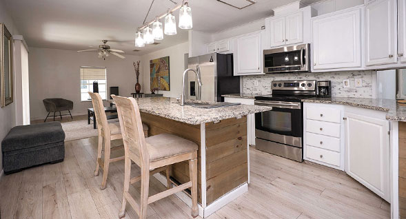 Upgraded white kitchen with granite center island, stainless steel appliances, pendant lighting and bar seating.